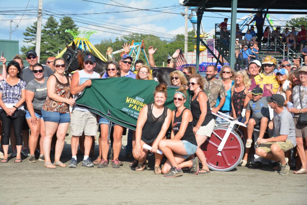 Large group posing at fair with horse